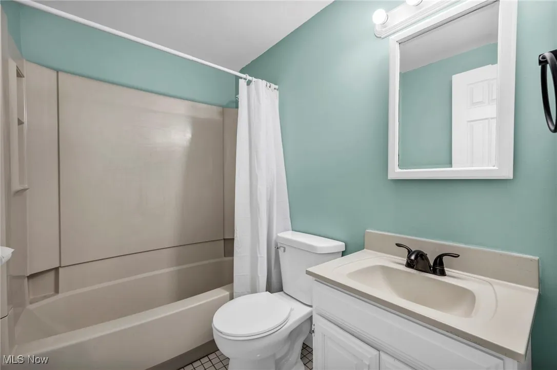 Full bath with shower / bath combo, vanity, and tile patterned floors