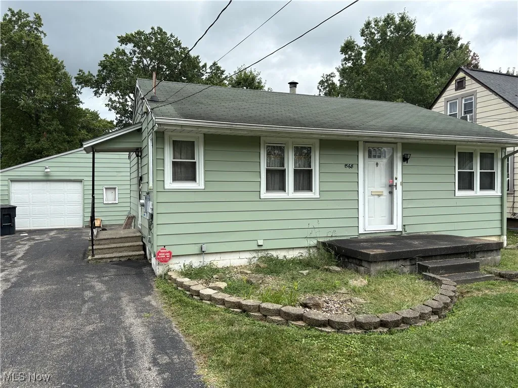View of front of property featuring asphalt driveway and a shingled roof