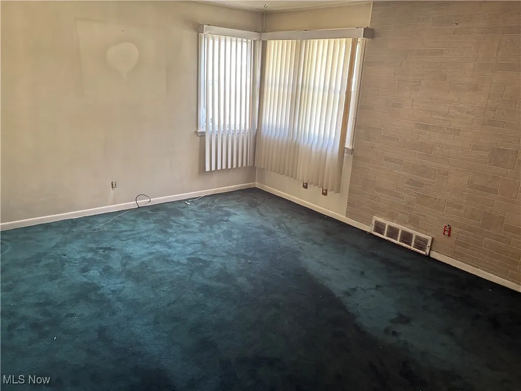 Spare room with baseboards and dark carpet