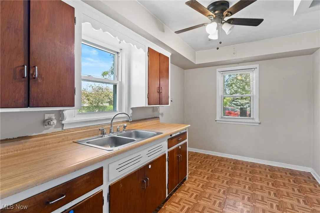 Eat in kitchen featuring ceiling fan, ample natural light and double sink.