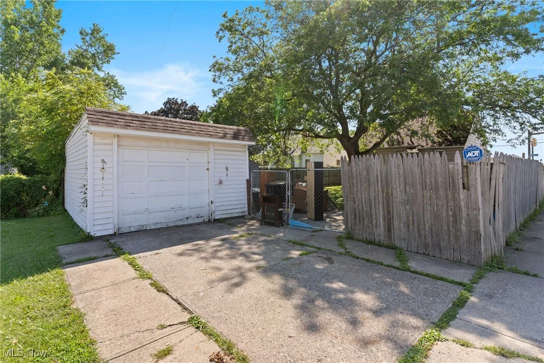 Detached 1 car garage featuring concrete driveway and a gate