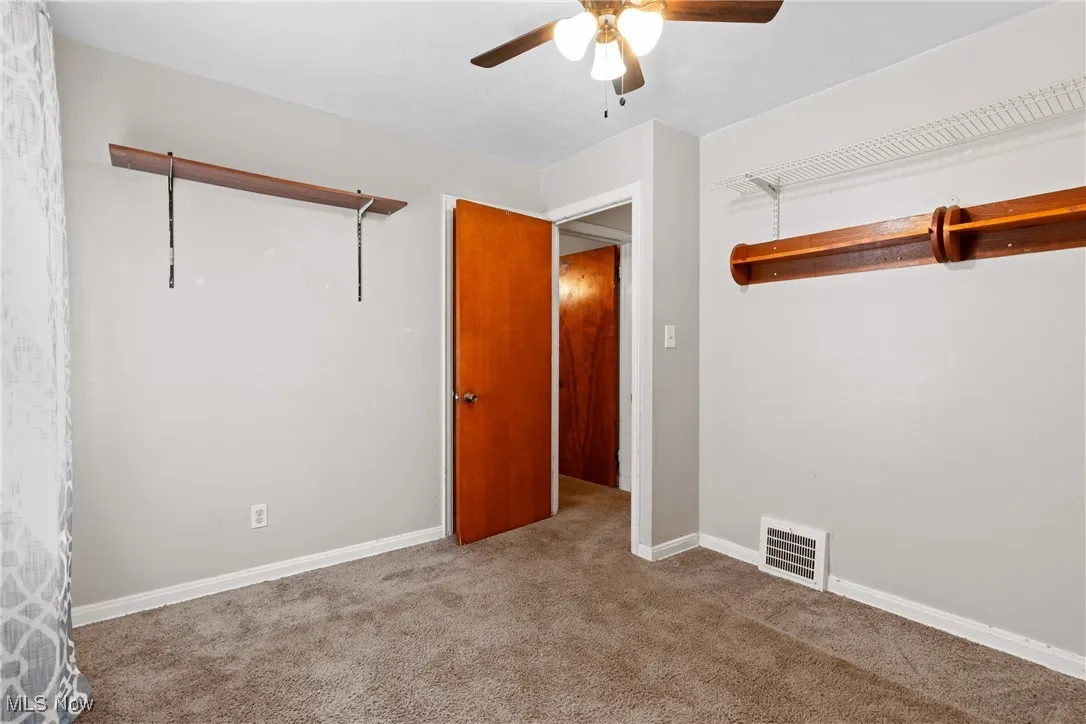 Carpeted spare room featuring ceiling fan and baseboards