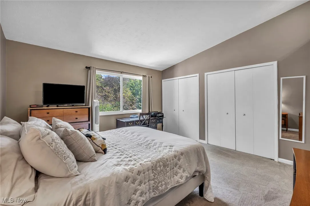 Owners Bedroom featuring vaulted ceiling, carpet flooring double closets