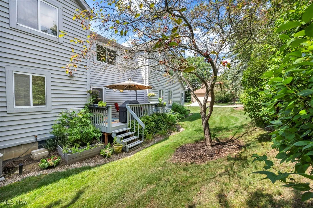View of lawn with a wooden deck and landscape
