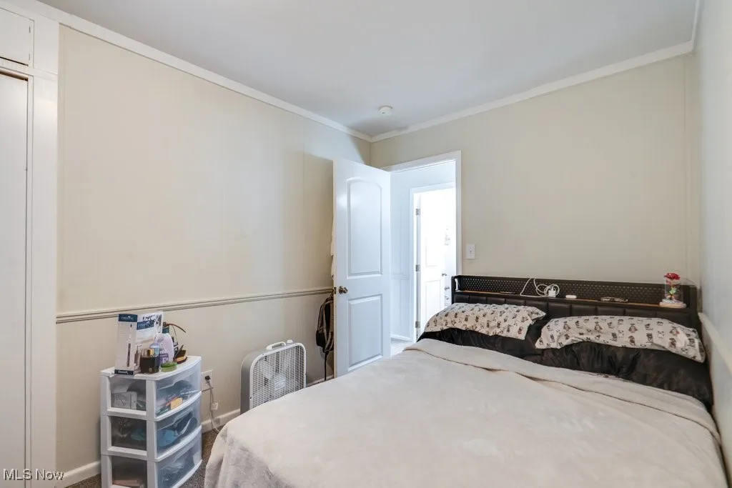 Carpeted bedroom with ornamental molding and baseboards