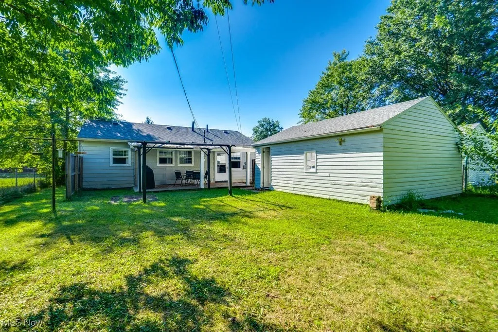 Rear view of property with a patio, a pergola, and roof with shingles