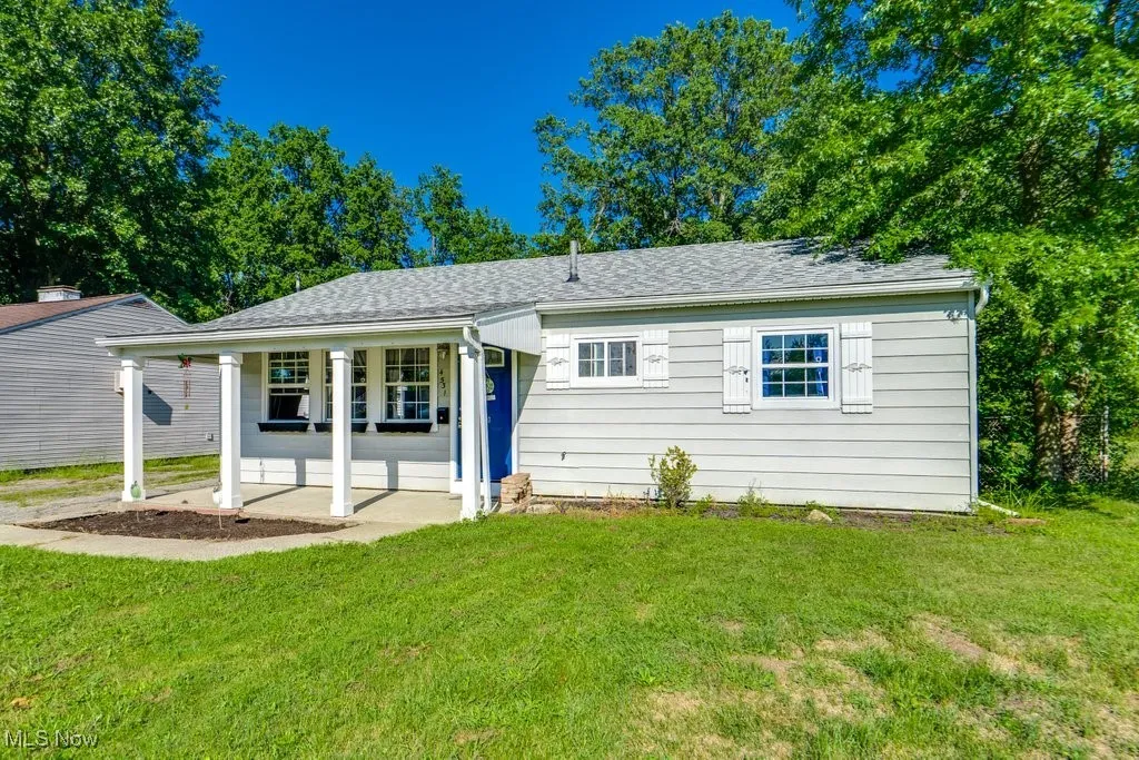 View of front facade featuring roof with shingles, a front lawn, and covered porch