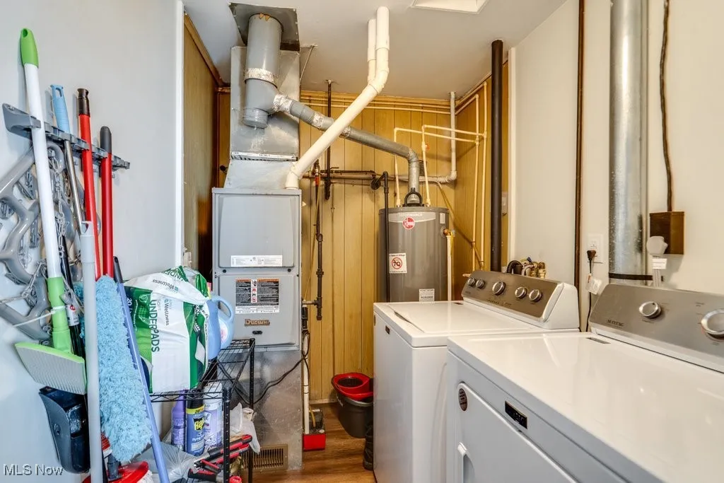 Laundry area featuring washer and clothes dryer, wood finished floors, gas water heater, and heating unit