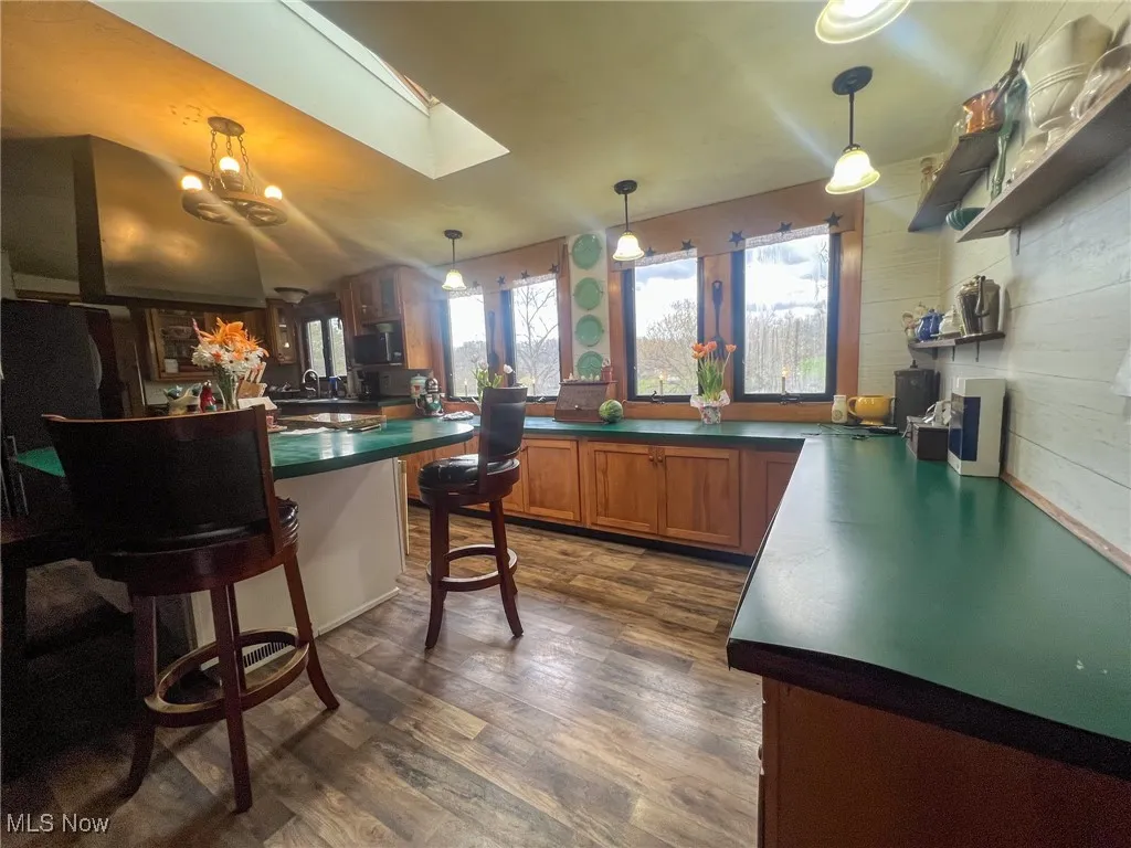 Kitchen with dark countertops, a kitchen bar, decorative light fixtures, and brown cabinets