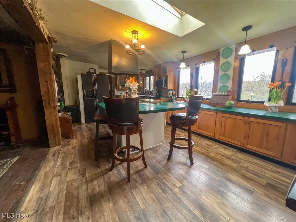 Kitchen with brown cabinets, dark countertops, dark wood-style floors, and a skylight