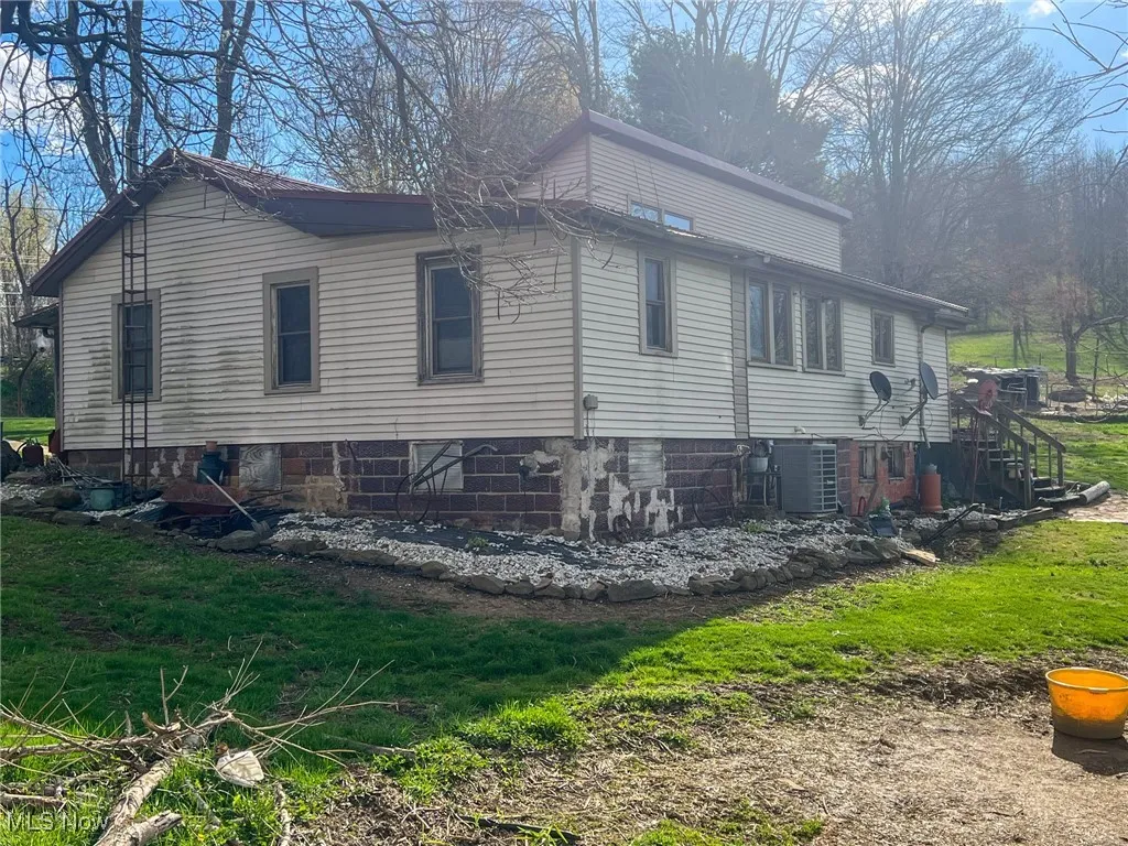 View of property exterior with a cooling unit and a yard