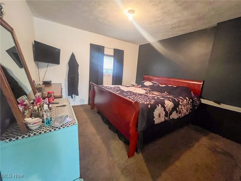 Bedroom featuring a textured ceiling and dark colored carpet