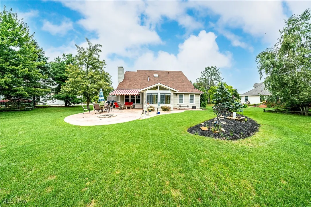 Back of house featuring a patio area, a yard, and a chimney
