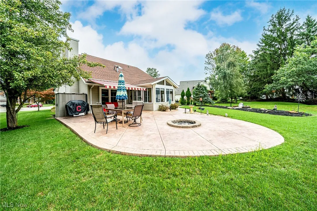 Rear view of property featuring a patio, a sunroom, an outdoor fire pit, and a lawn