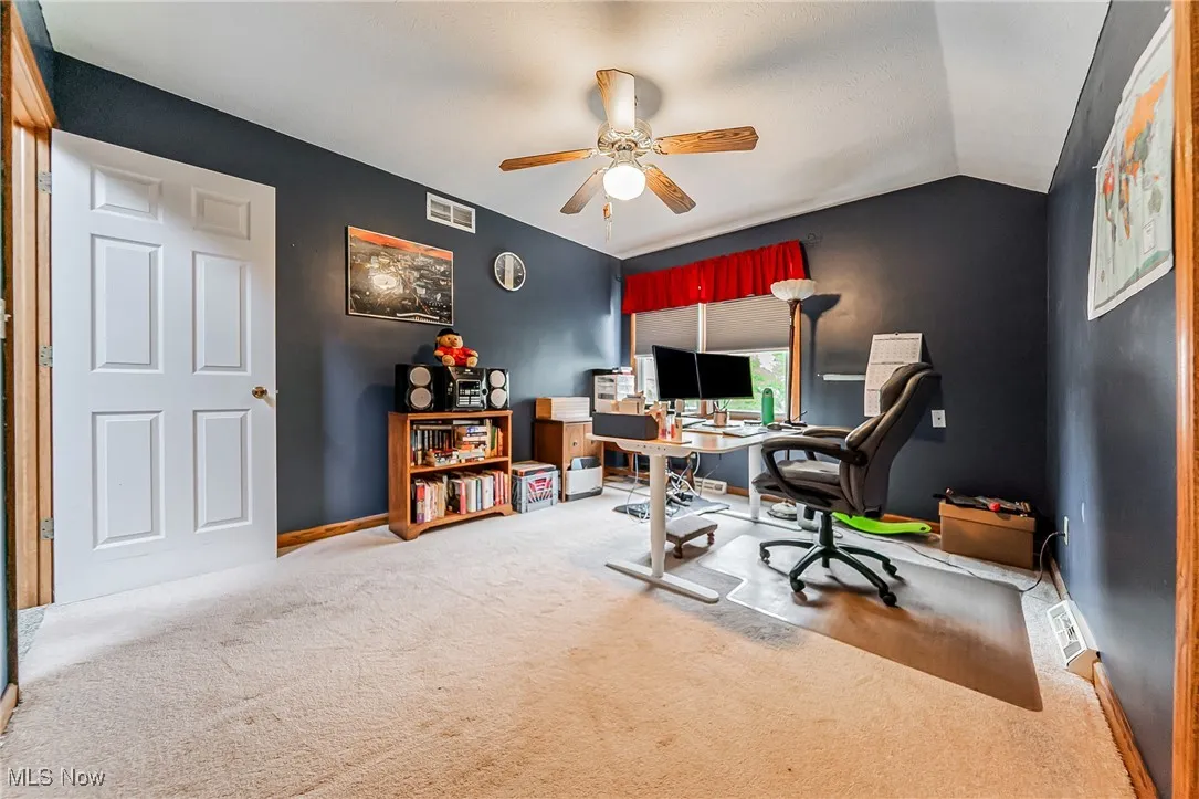 Office area with carpet floors, vaulted ceiling, and a ceiling fan