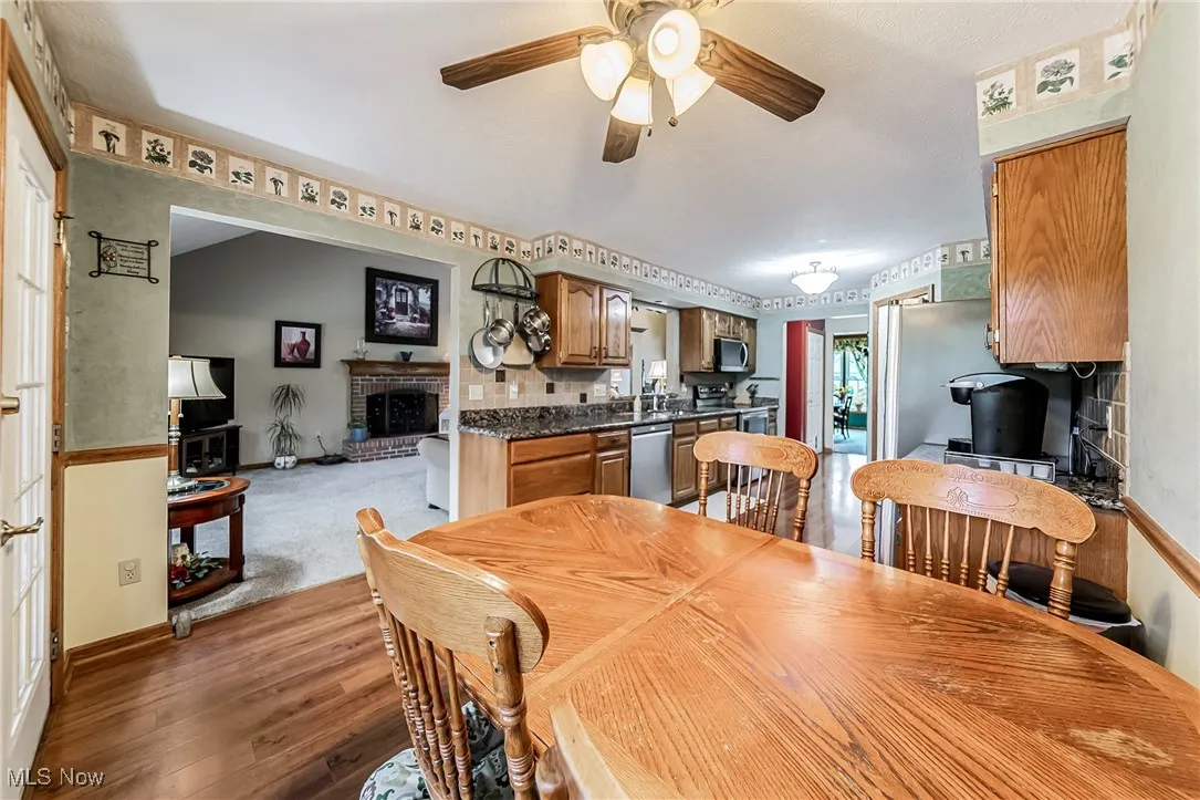 Dining area featuring light wood finished floors, a ceiling fan, a fireplace, and light carpet