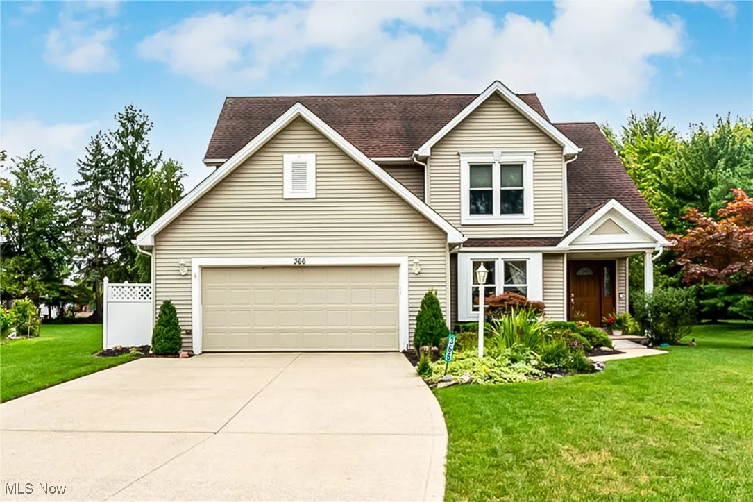 Traditional home with a front lawn, driveway, an attached garage, and roof with shingles