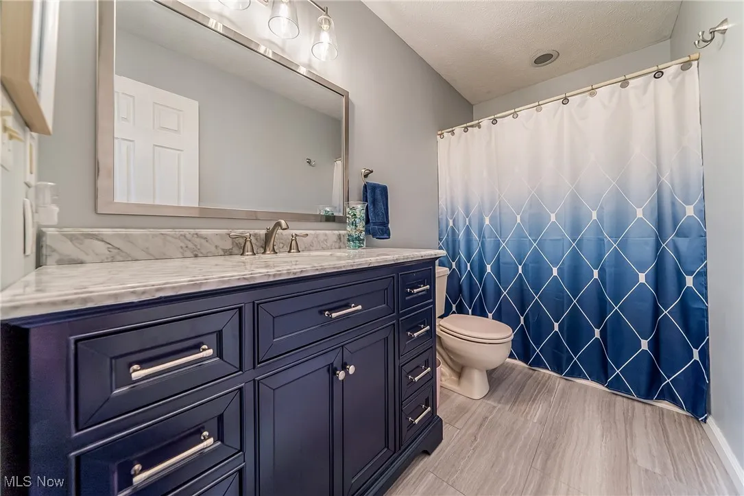 Full bathroom featuring vanity, a textured ceiling, and a shower with curtain
