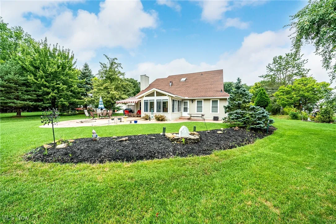 Rear view of house with a lawn, a sunroom, a patio area, and a chimney