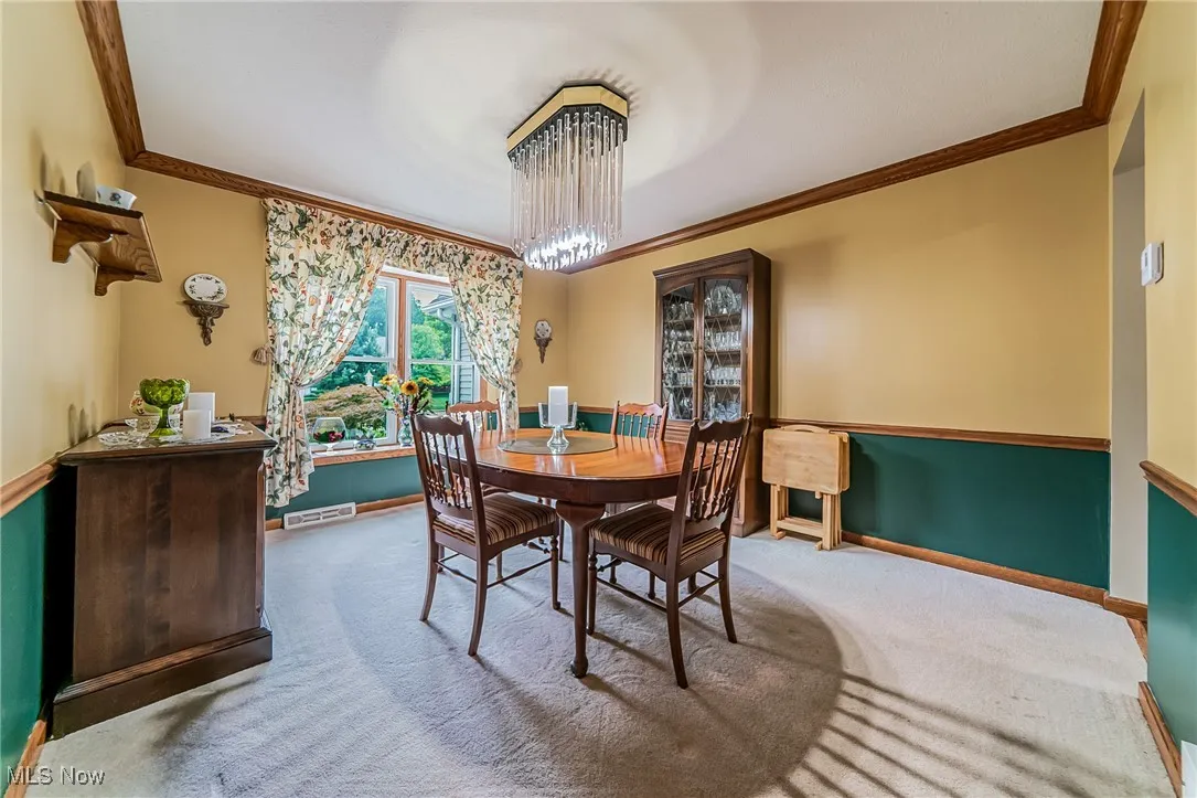 Carpeted dining room featuring crown molding and a chandelier