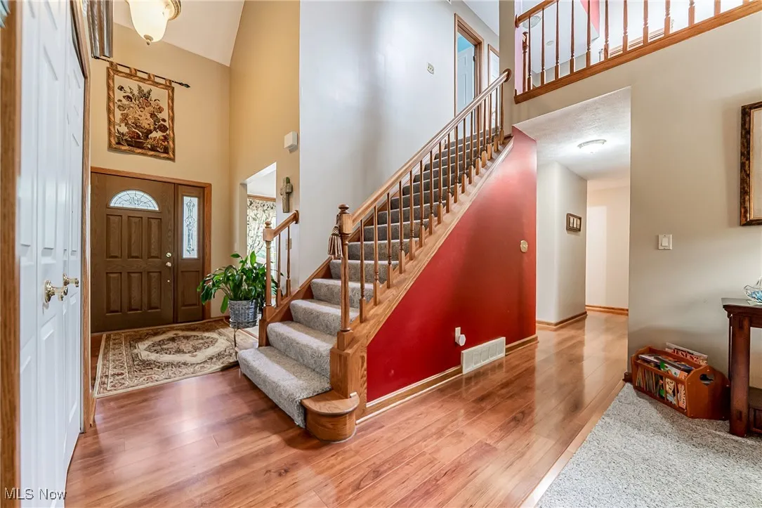 Entryway with a high ceiling, stairway, and wood finished floors