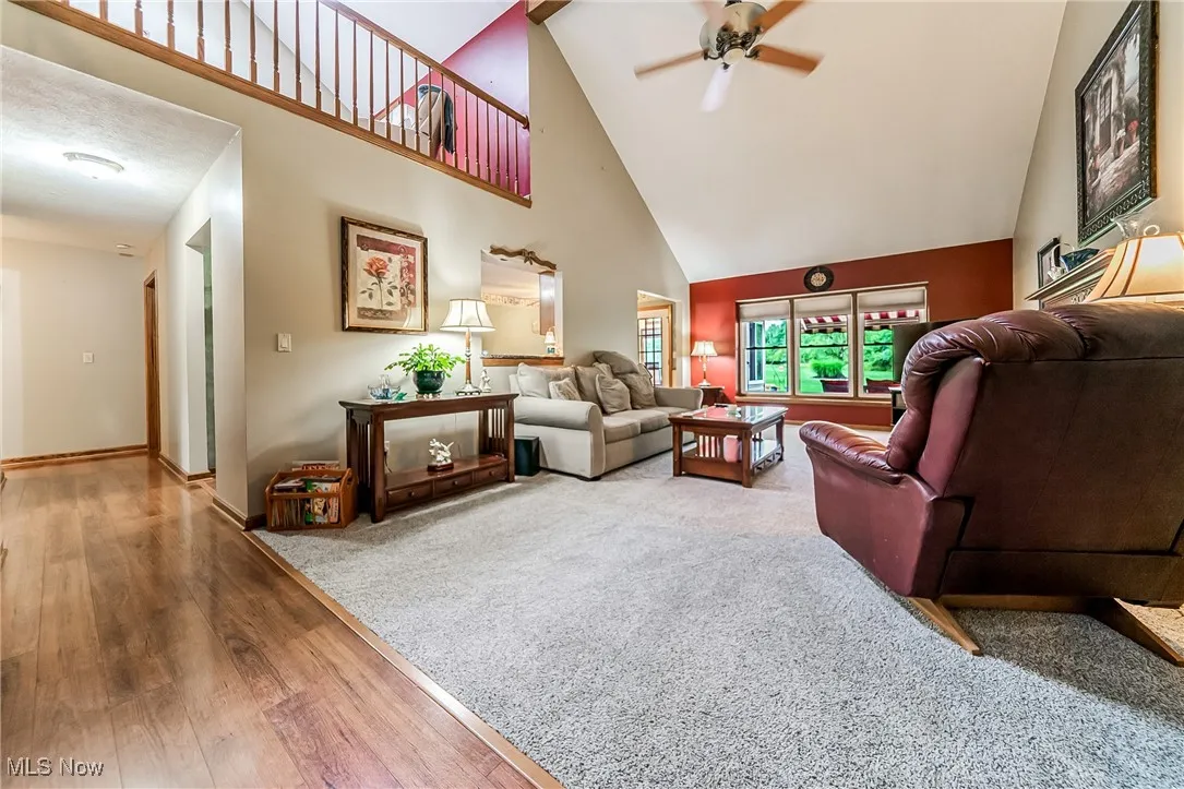 Living area featuring high vaulted ceiling, wood finished floors, and a ceiling fan