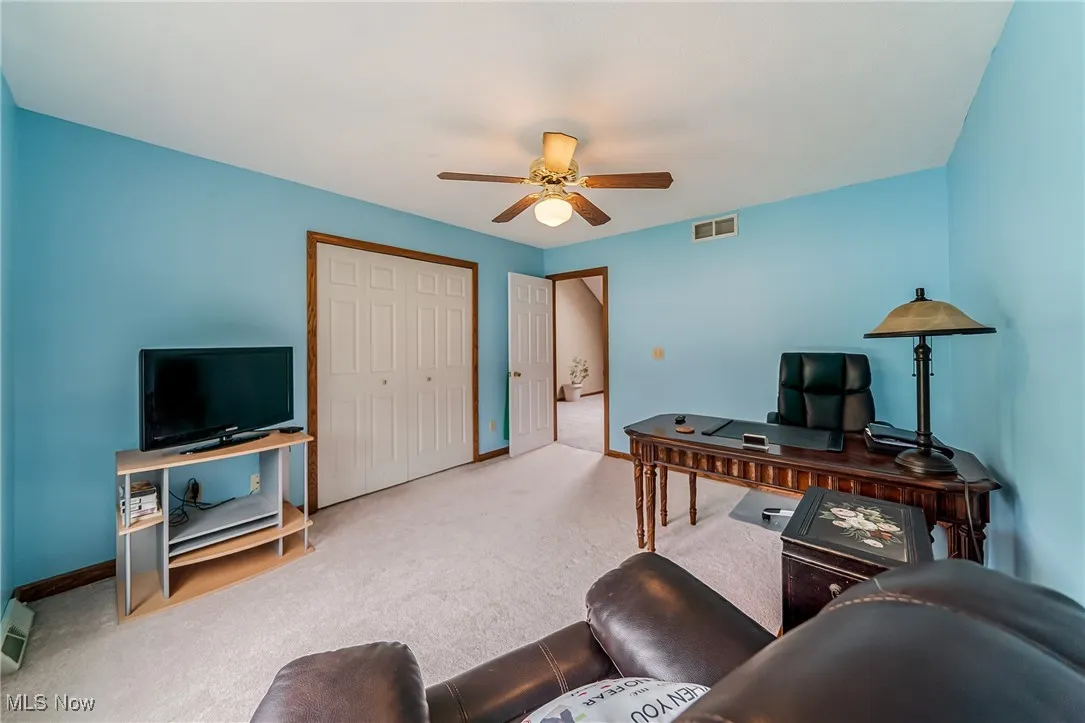 Carpeted office featuring baseboards and a ceiling fan