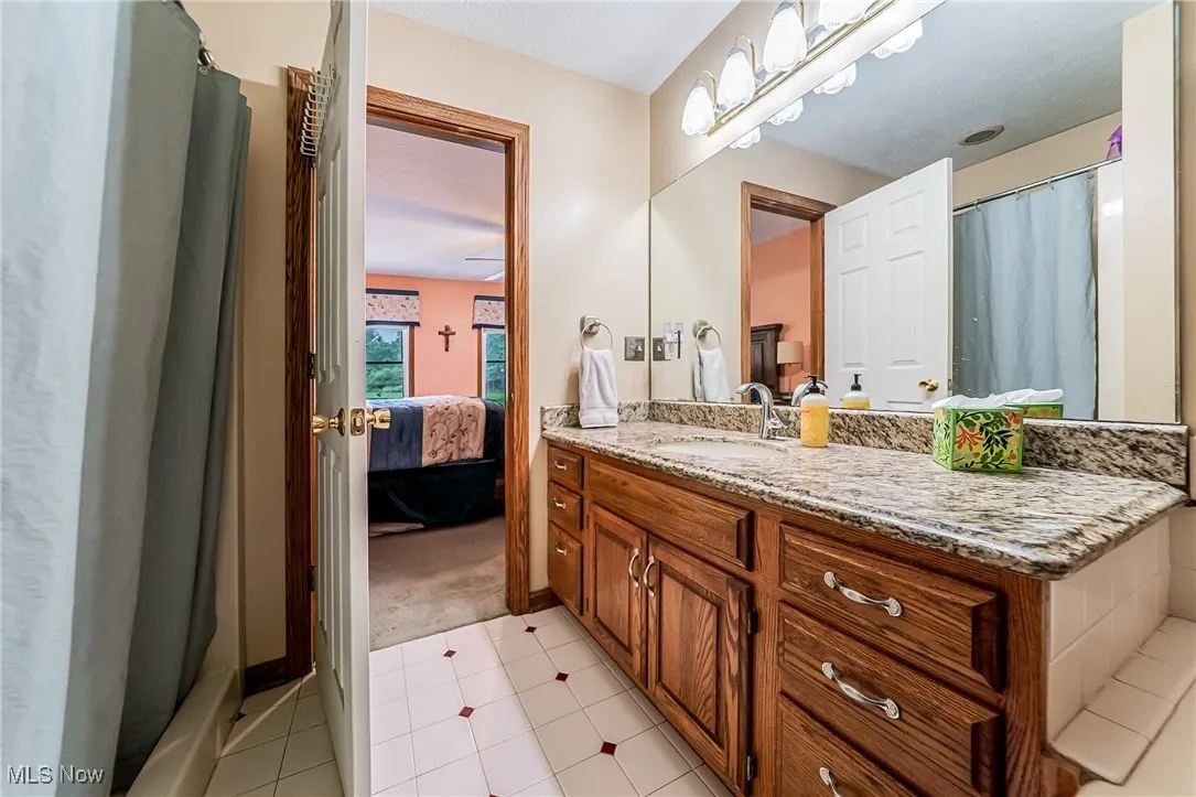 Ensuite bathroom featuring vanity, light tile patterned floors, and a shower stall