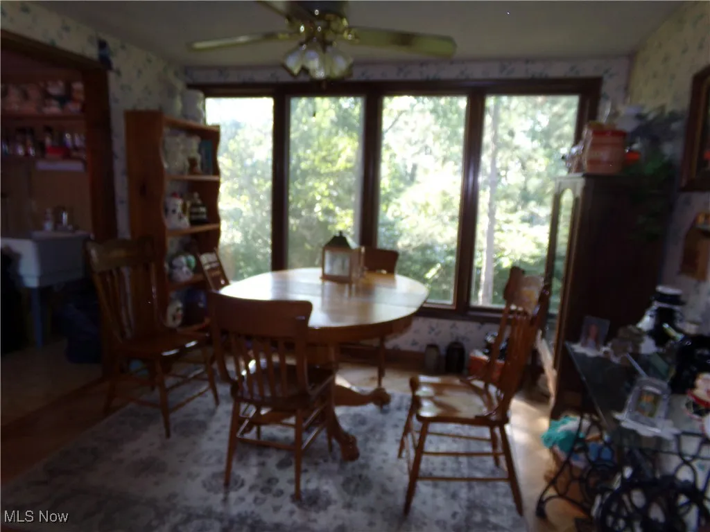 Dining room featuring wallpapered walls and a ceiling fan