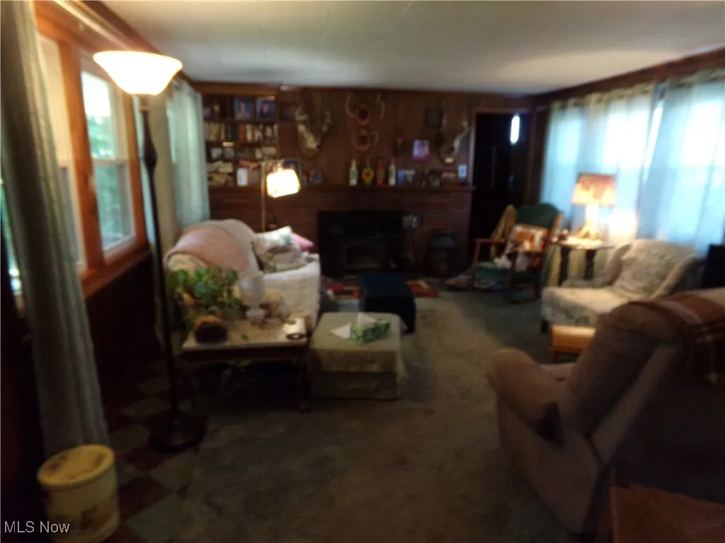 Carpeted living room featuring healthy amount of natural light, a brick fireplace, and wooden walls