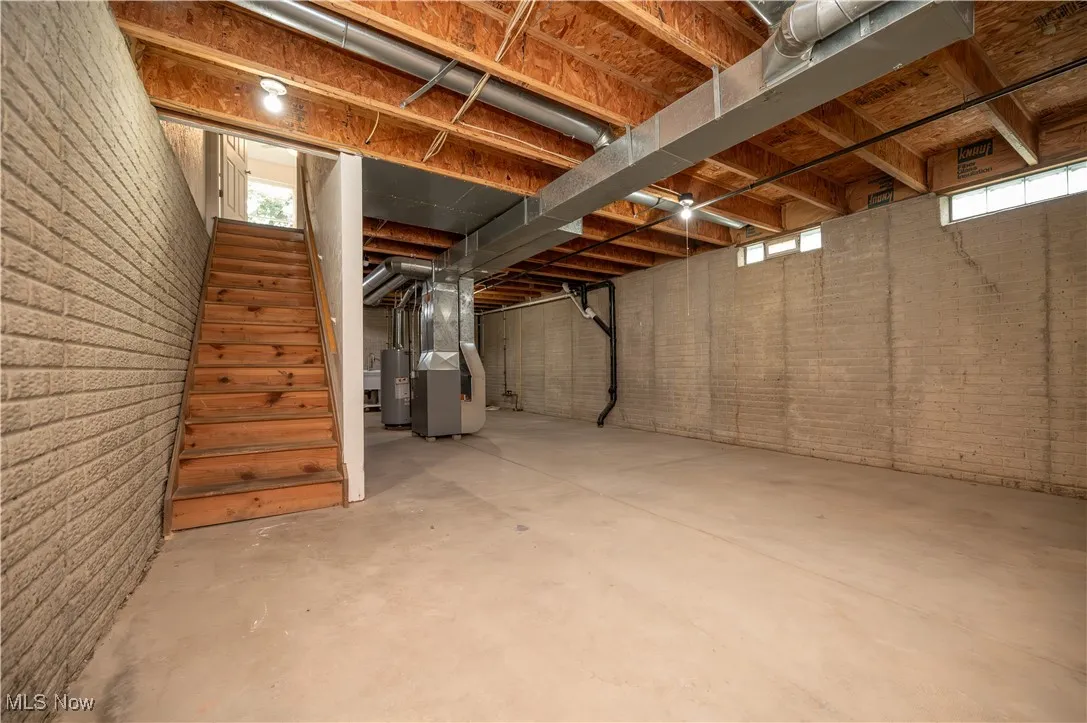Basement with stairs, heating unit, and water heater