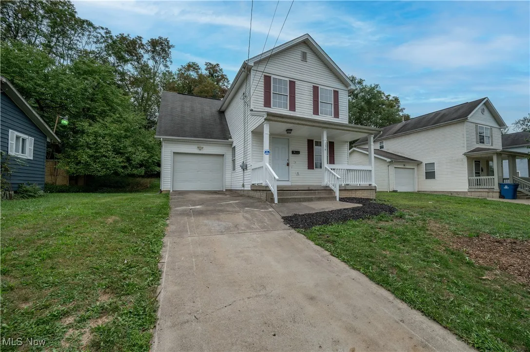 Traditional home featuring covered porch, concrete driveway, an attached garage, and a front lawn