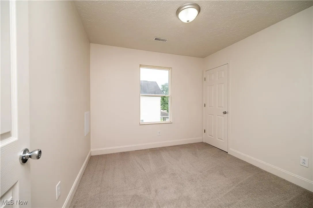 Spare room featuring light carpet and a textured ceiling
