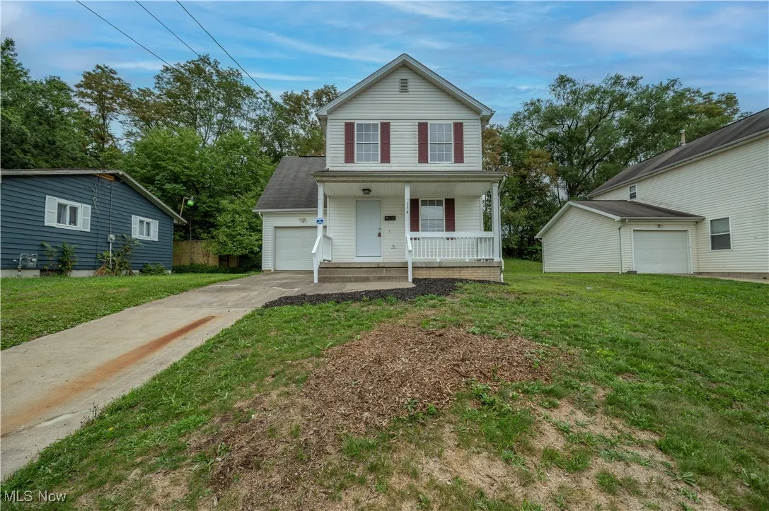 Traditional-style home with covered porch, concrete driveway, a front yard, and a garage