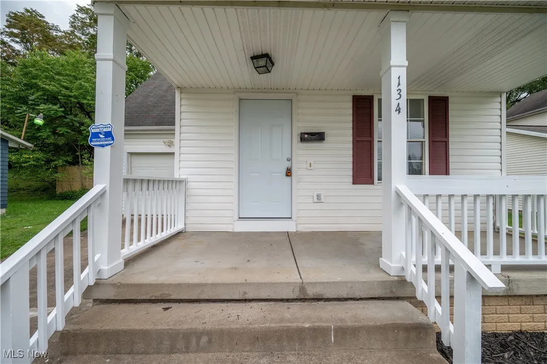 Doorway to property with a porch, a garage, and roof with shingles