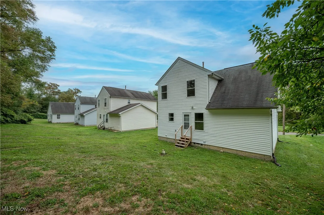 Back of house featuring a yard, roof with shingles, and entry steps