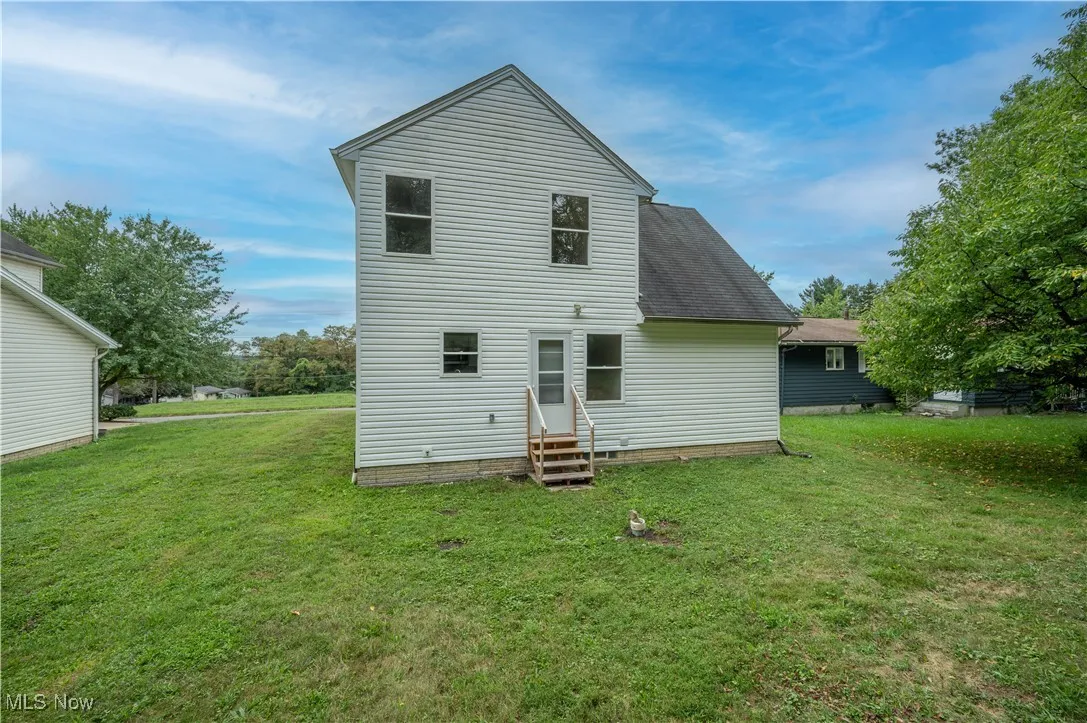 Back of property with a yard, entry steps, and a shingled roof