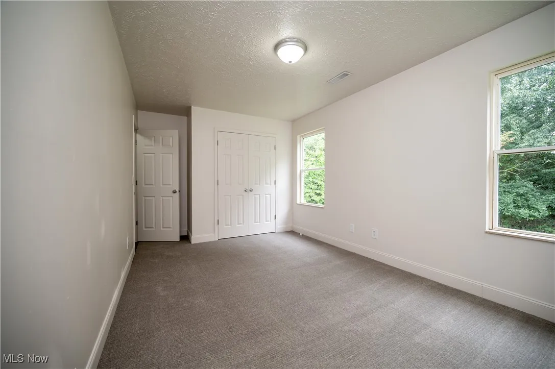 Unfurnished bedroom featuring carpet, a textured ceiling, and a closet