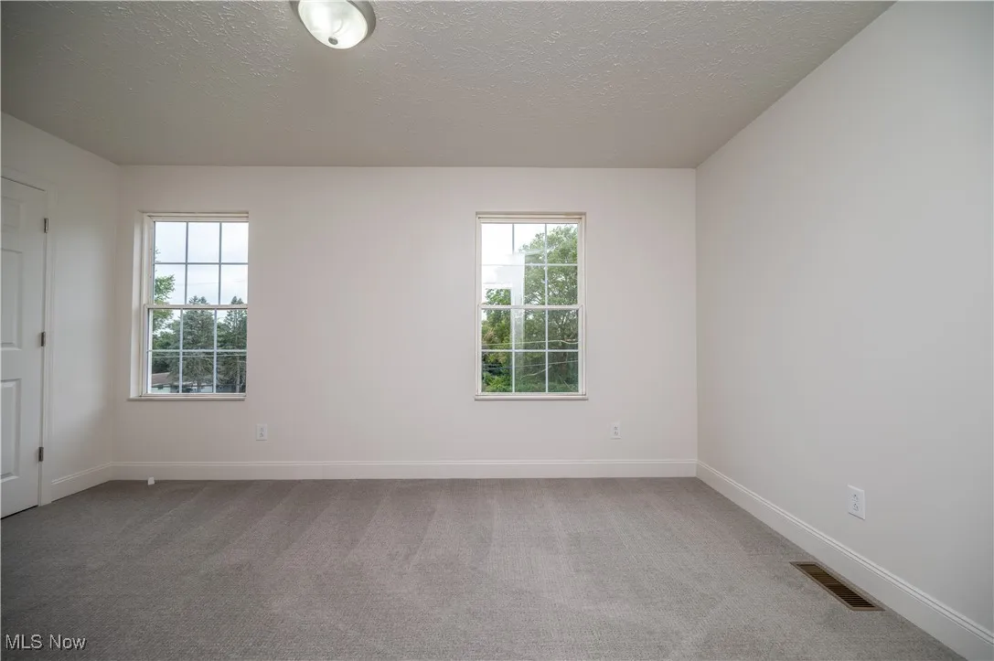 Spare room featuring light carpet and a textured ceiling