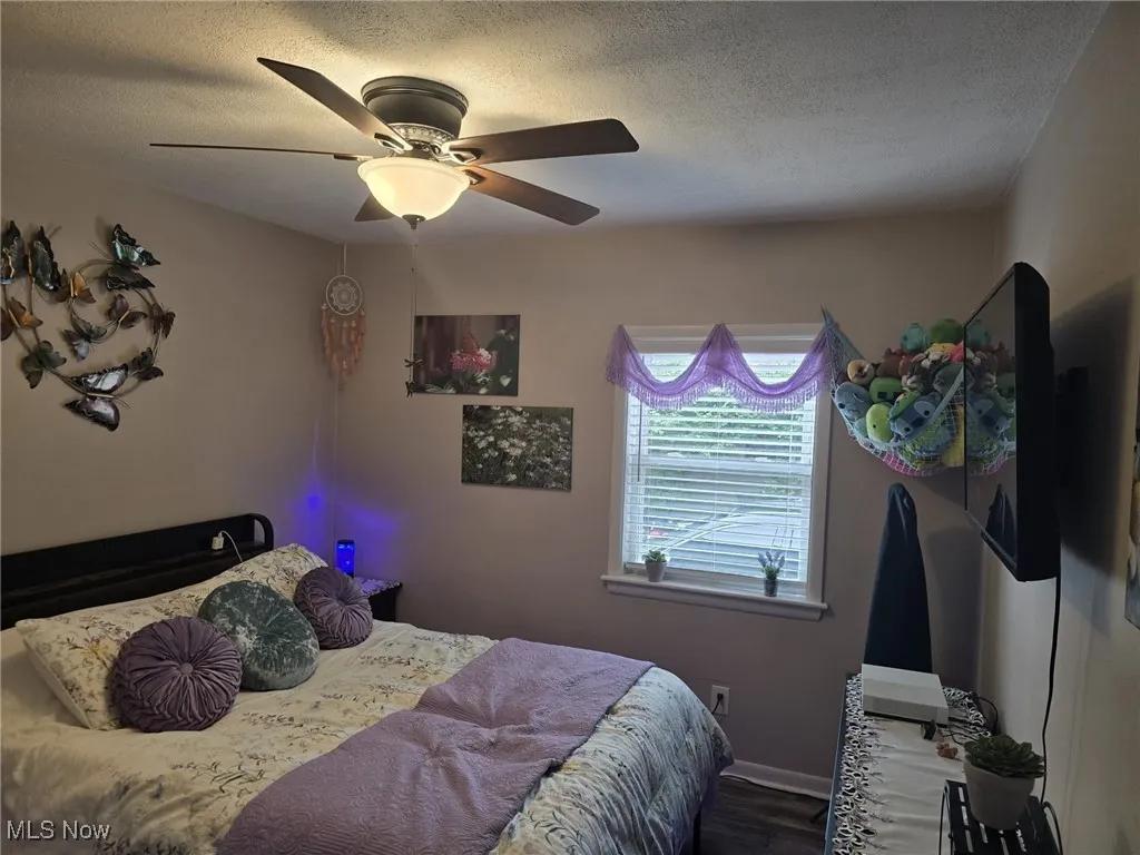Bedroom featuring a textured ceiling, ceiling fan, and wood finished floors