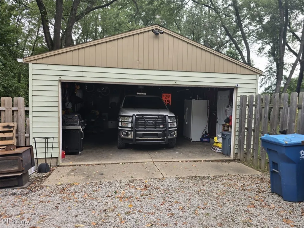 Detached garage with man door and view of wooded area