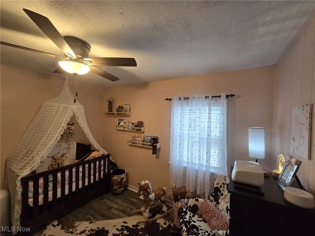 Nice size bedroom, a textured ceiling, wood finished floors, and a ceiling fan