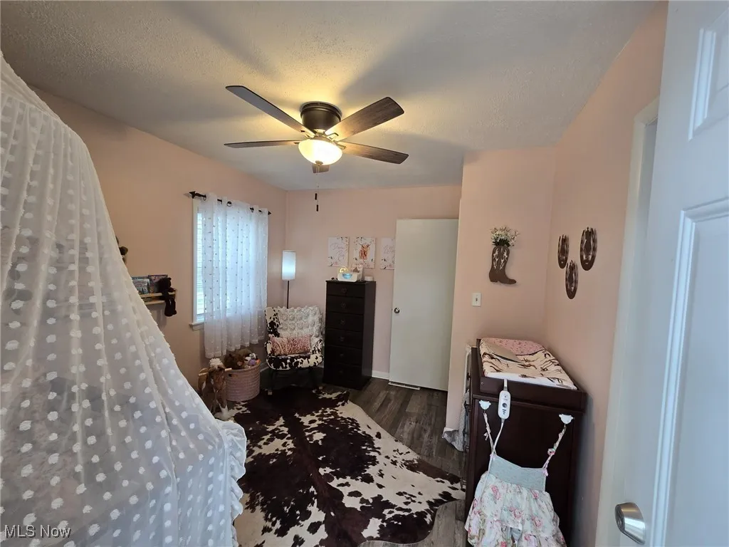 Bedroom featuring dark wood-type flooring, a ceiling fan, and a textured ceiling