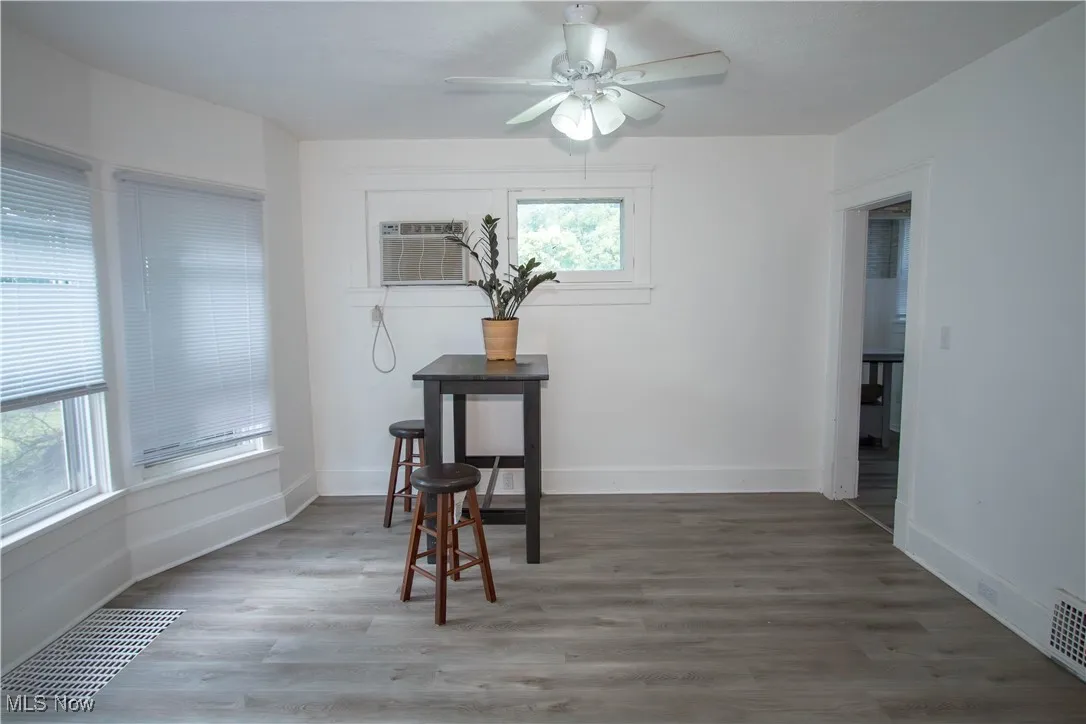 Dining area with light wood finished floors, ceiling fan, and a wall mounted air conditioner