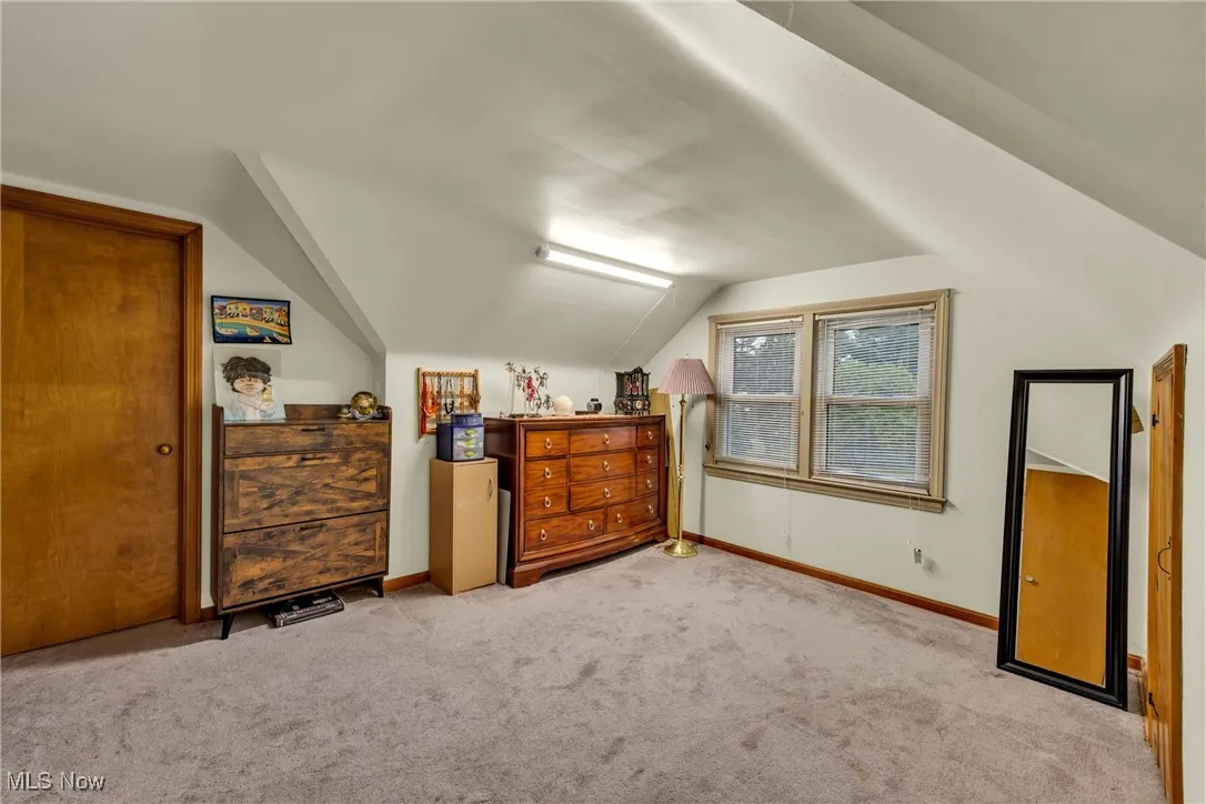 Additional living space with light carpet and lofted ceiling