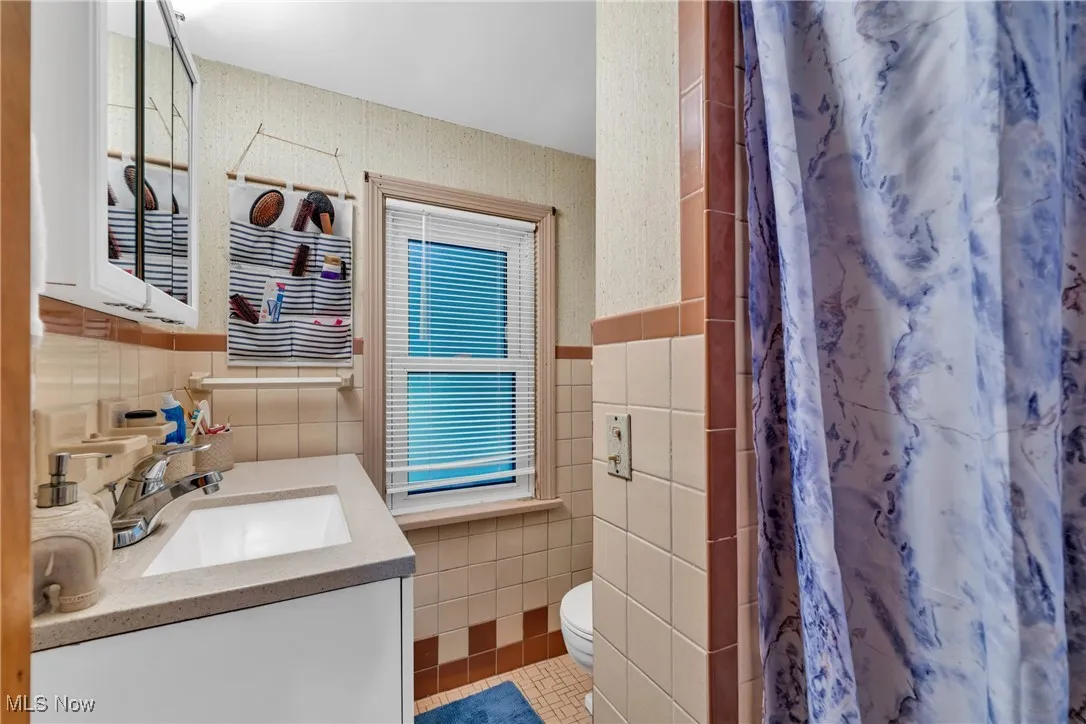 Bathroom with vanity, tile walls, light tile patterned floors, a shower with curtain, and wallpapered walls