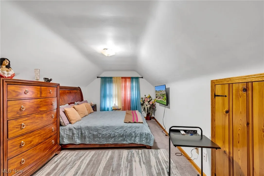 Bedroom with lofted ceiling and light carpet