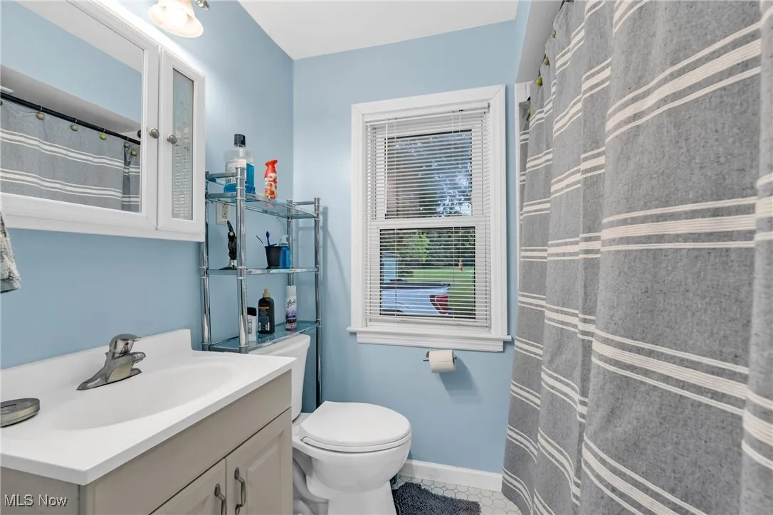 Full bath with vanity, light tile patterned floors, and a shower with shower curtain