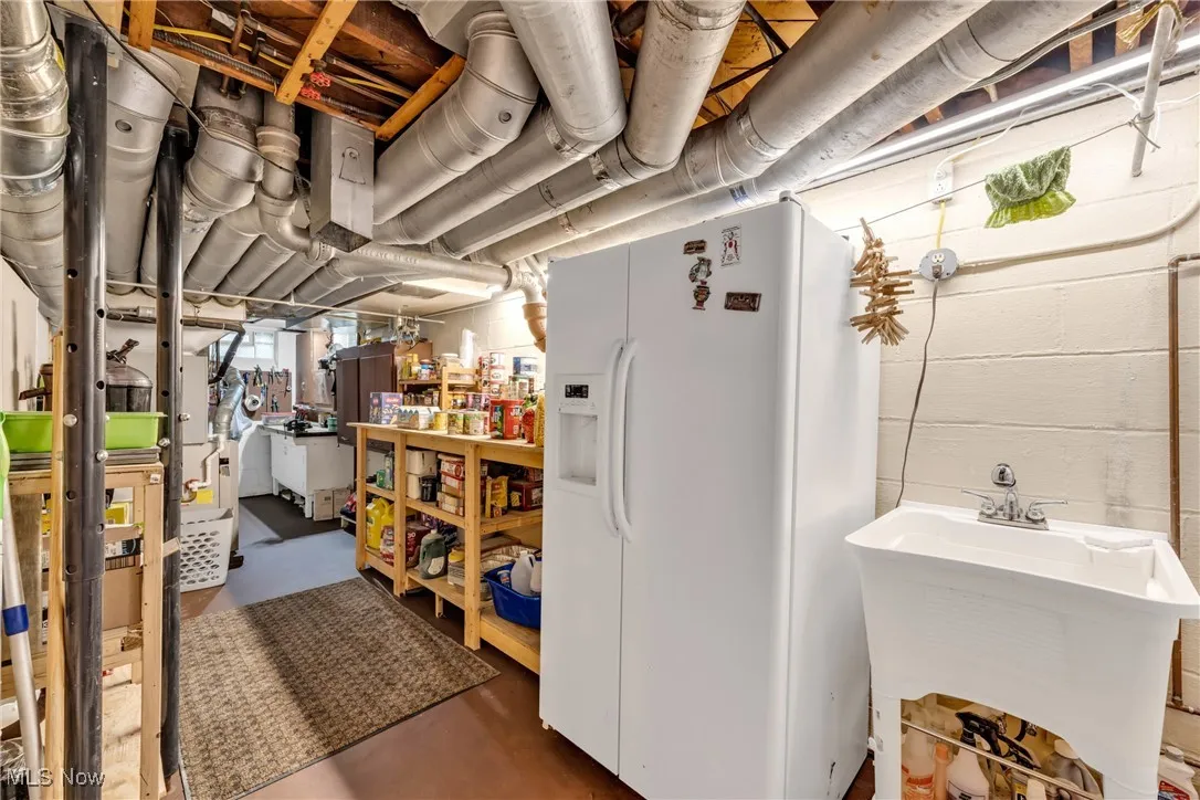 Below grade area with white fridge with ice dispenser and a sink