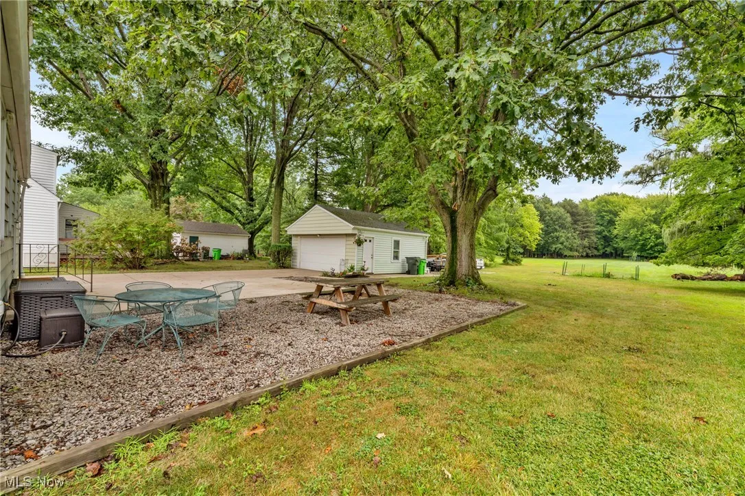 View of green lawn with a patio area, an outdoor structure, and a garage